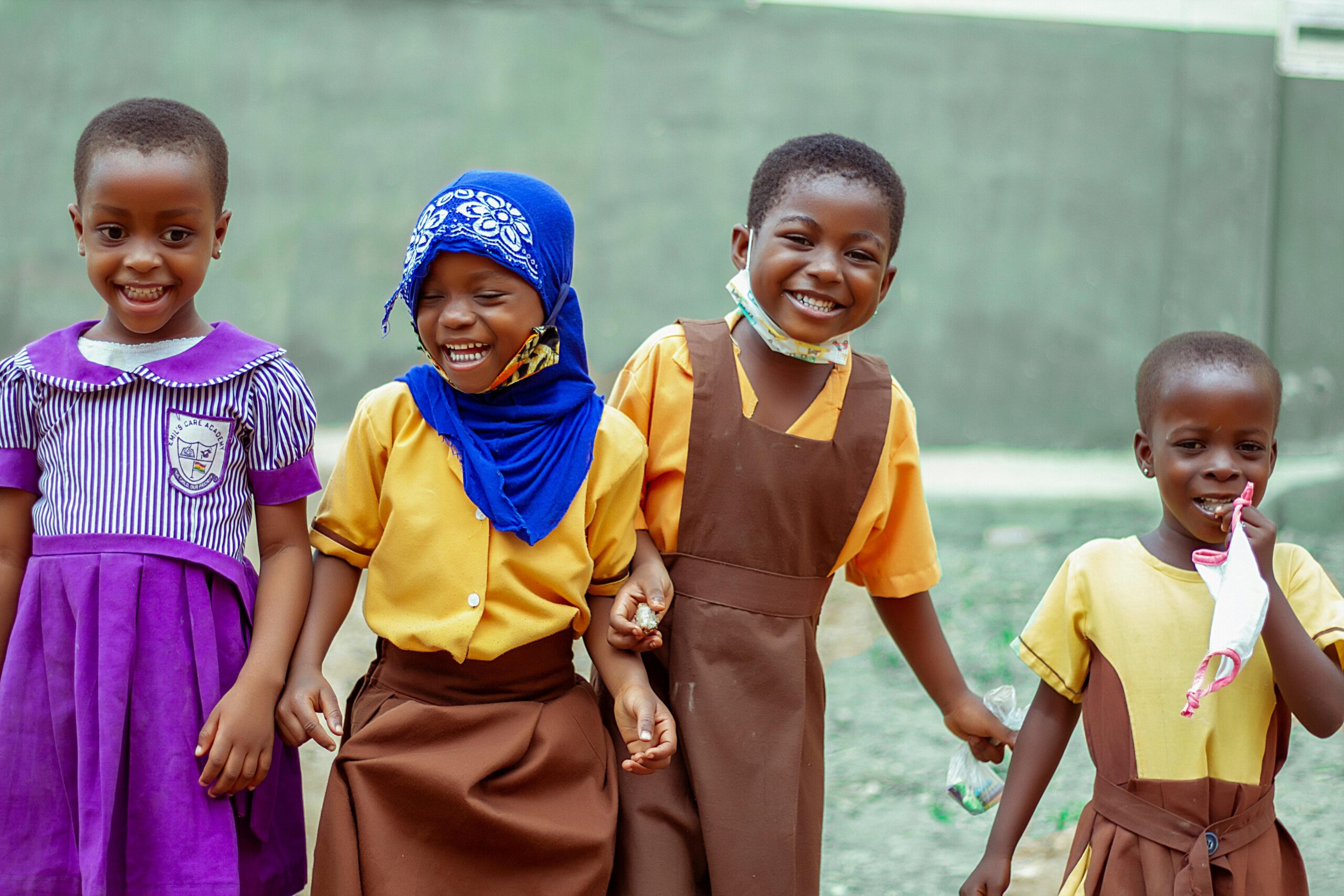 Happy children in school uniforms smiling and enjoying break time outside in Accra, Ghana.